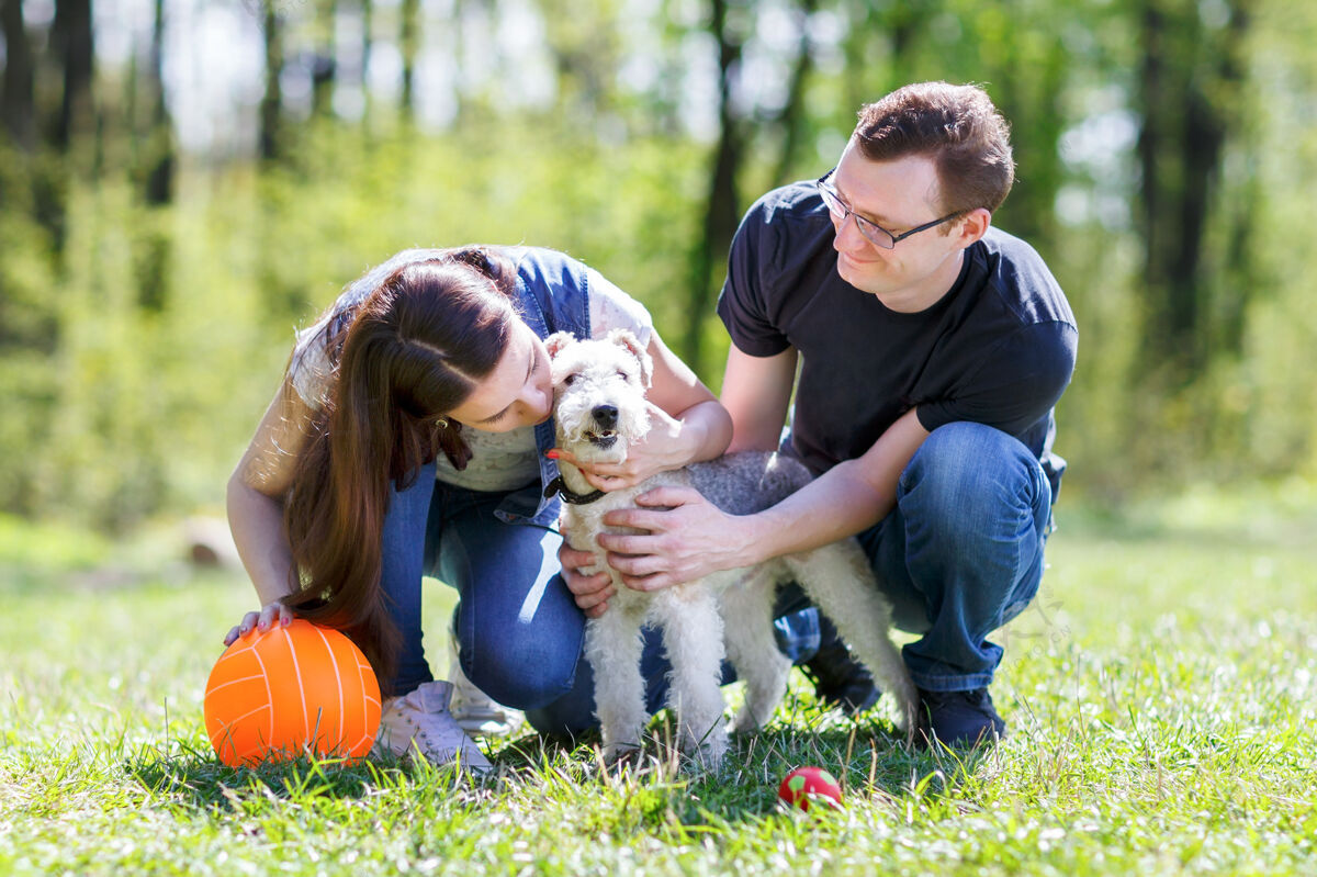 男人快乐的家庭在夏季公园拥抱一只狗英俊可爱年轻