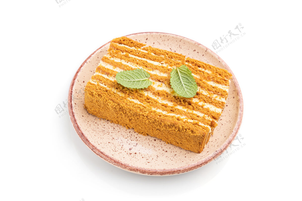 奶油自制蜂蜜蛋糕与牛奶奶油和薄荷隔离在白色表面质地盘子糕点