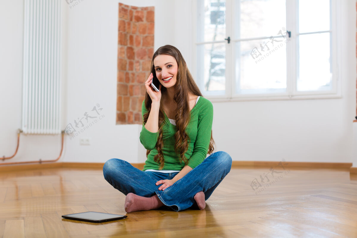 房子坐在家里地板上打电话的年轻女子电话休息回家时间