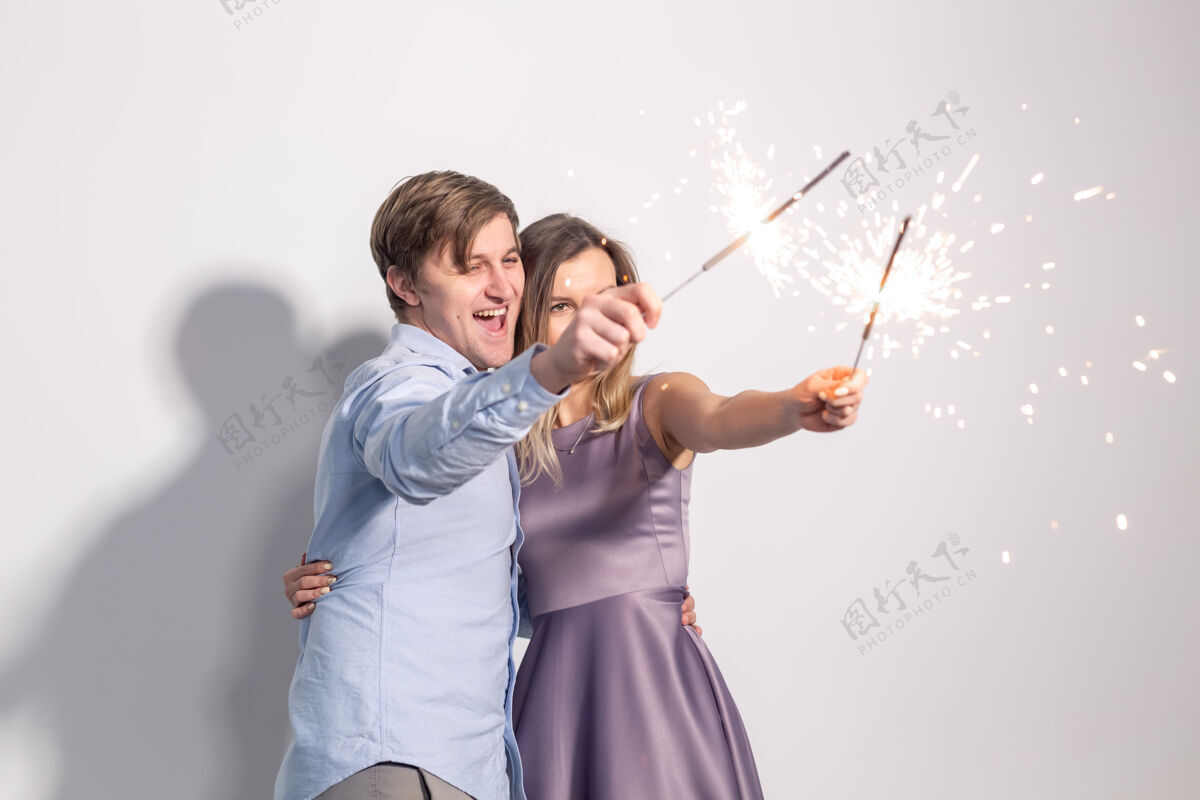 微笑派对乐趣和假期的概念年轻幸福的夫妇与白色墙壁上的火花光爱情快乐