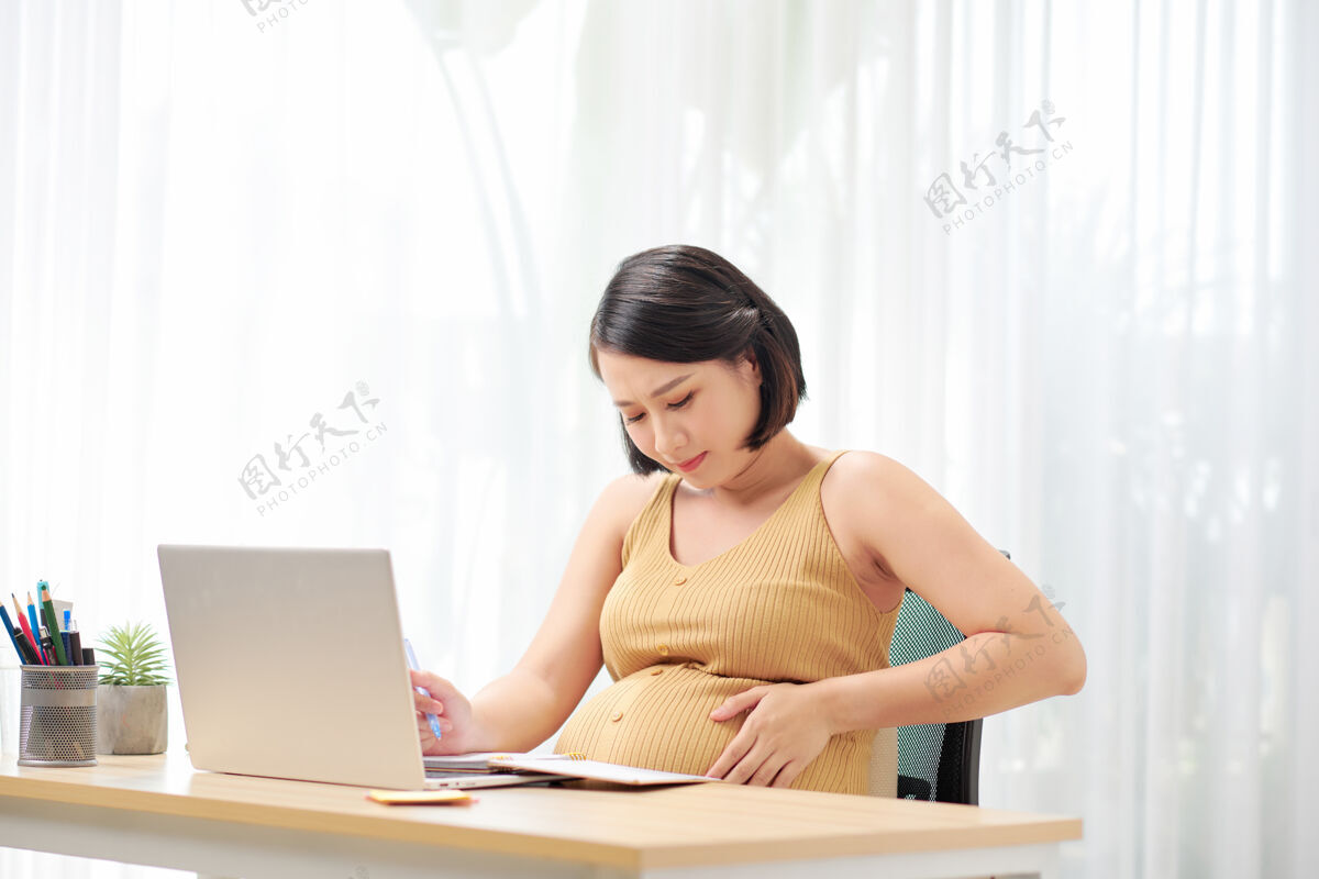 笔记本电脑怀孕的自由职业者摸肚子附近的笔记本电脑室内母亲韩国人