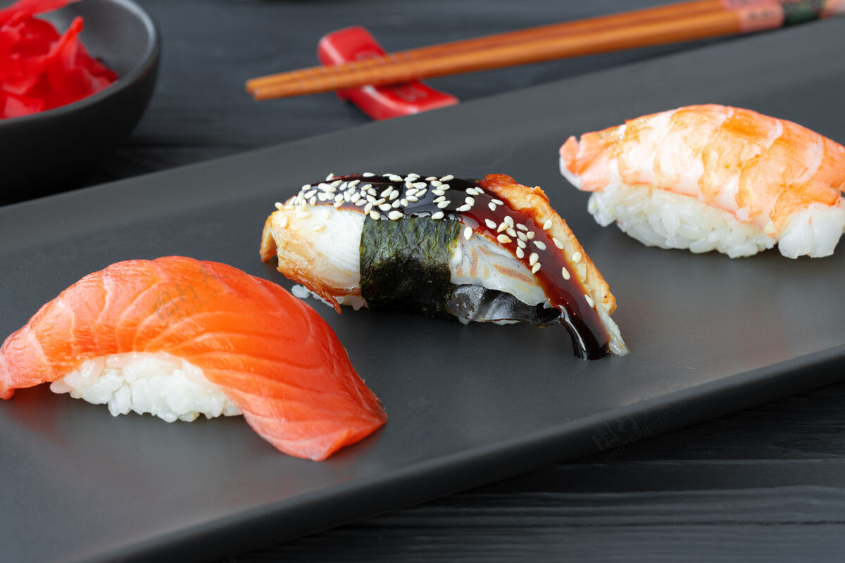 海鲜黑陶瓷盘上有三文鱼鳗鱼和大虾的尼吉里寿司米饭生鱼片鱼
