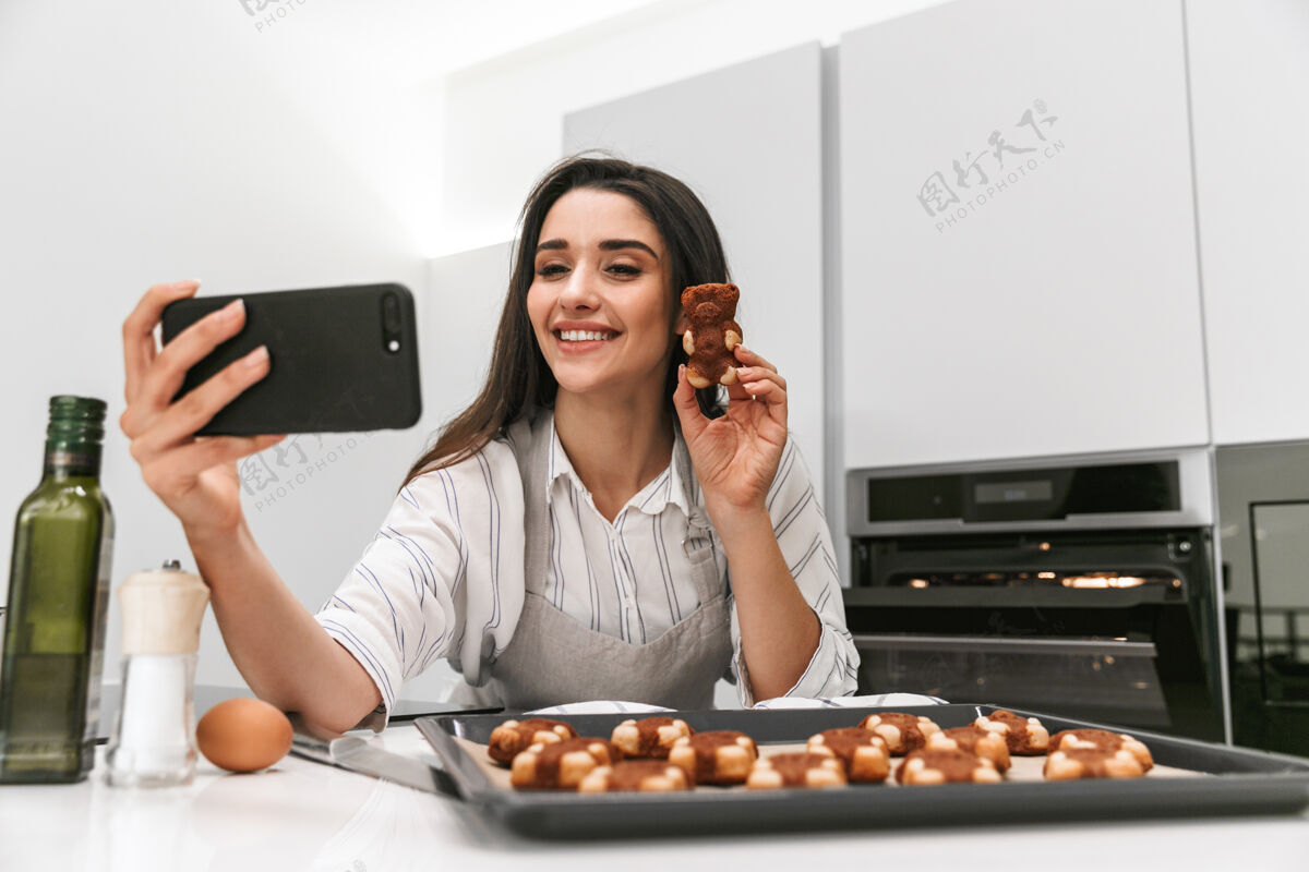 饼干迷人的年轻女子站在厨房自拍时 正在托盘上做美味的饼干烹饪托盘甜点