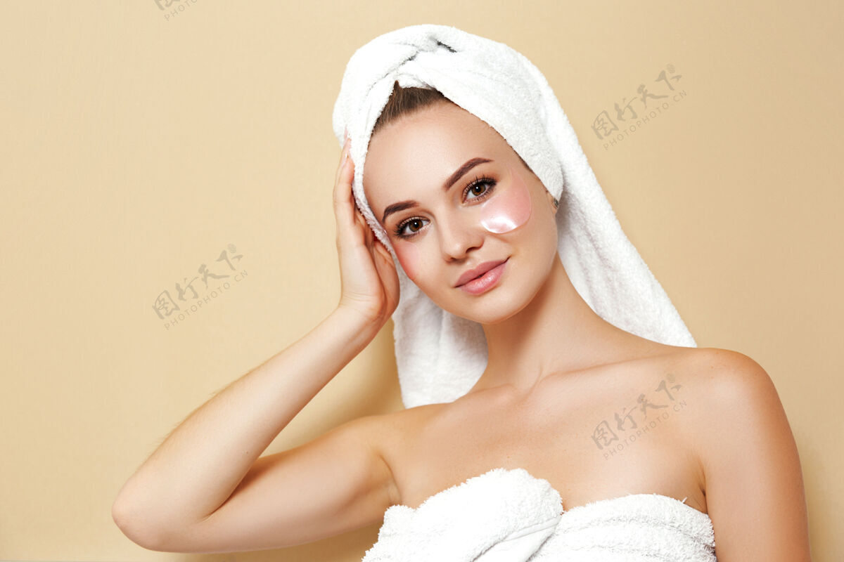 年轻化一个穿着白毛巾 脸上有补丁的女人摆姿势美容美容粉底