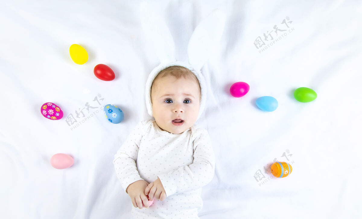 服装宝宝穿得像兔子 在白色的表面上放复活节彩蛋鸡蛋兔子童年