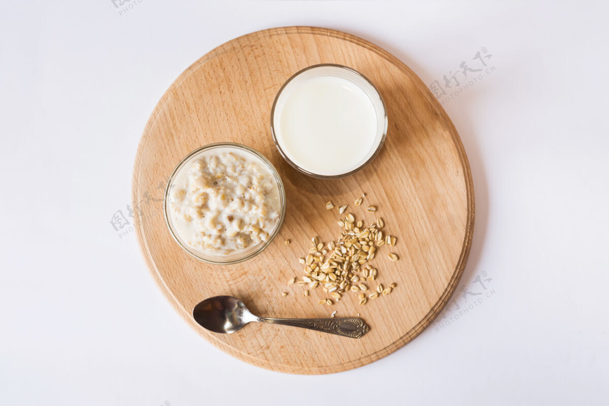营养在白色表面的木板上放一碗麦片和一杯牛奶从上面看种子食物薄片