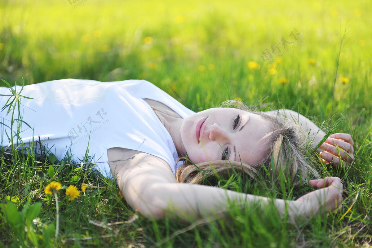 牛仔裤年轻漂亮的金发女郎正在公园的春天里休息放松金发散步