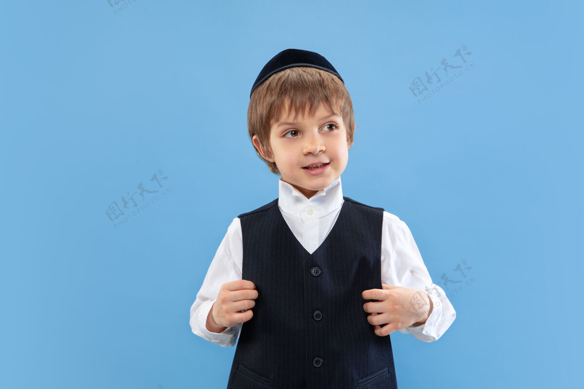 通信一个年轻的东正教犹太男孩的肖像被隔离在蓝色的工作室墙上犹太人年轻手