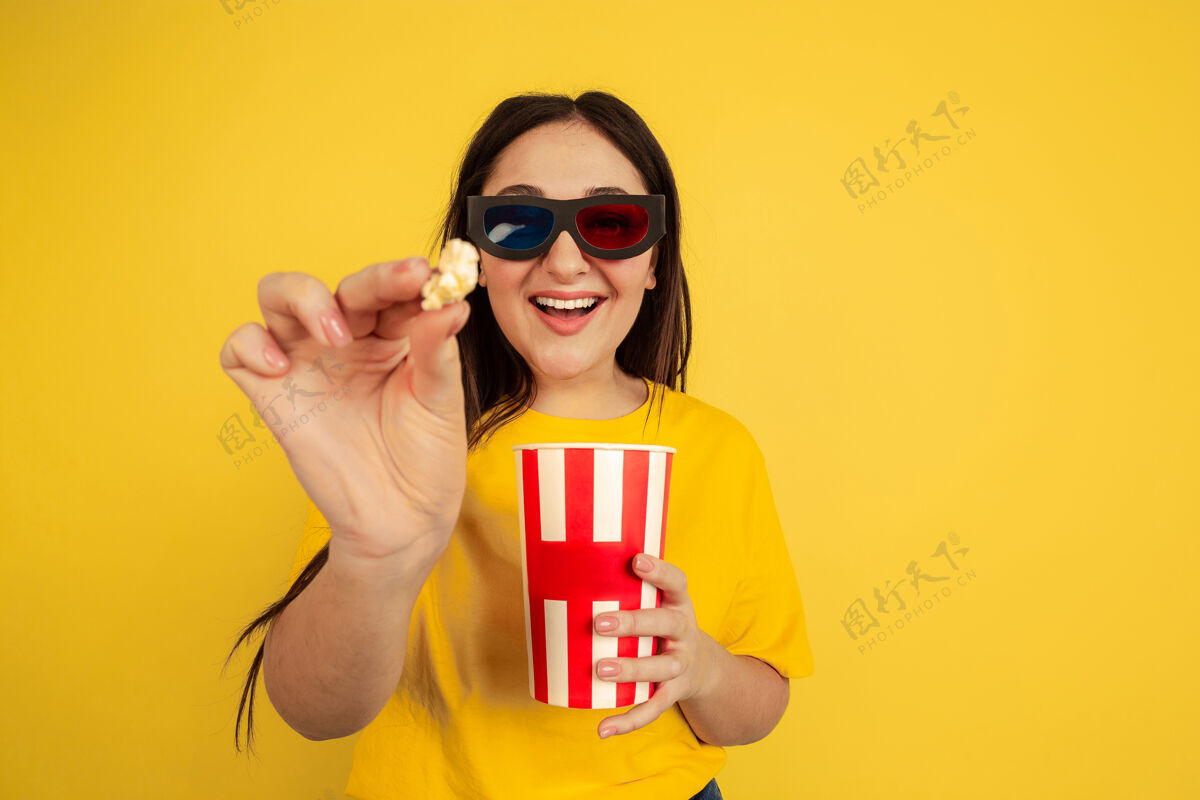 公司3d电影眼镜和爆米花隔离在黄色工作室背景上的白人女性肖像休闲风格的美丽模特人类情感 面部表情 销售 广告 复制空间的概念手女孩成功