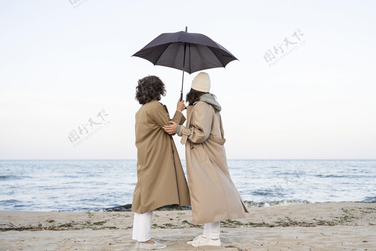 女人母女俩在沙滩上打着伞 分享着温柔的时刻团结雨伞在一起