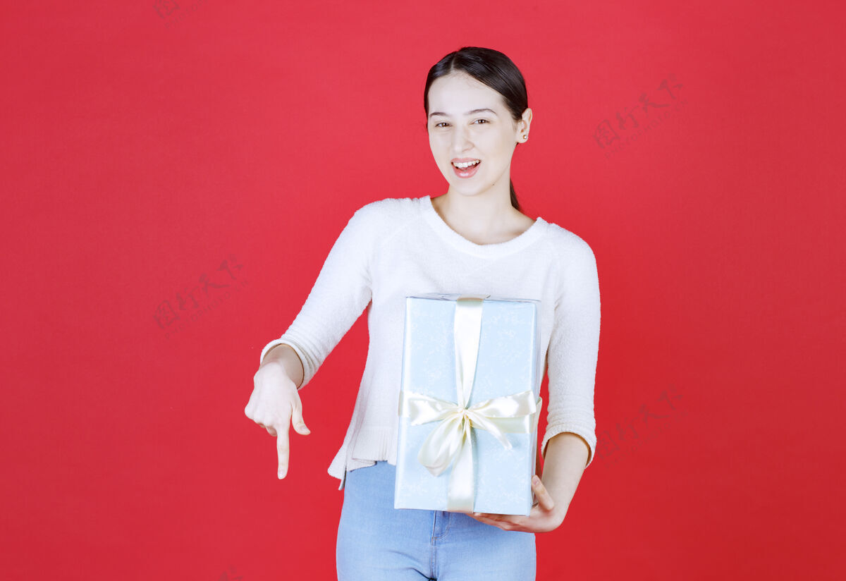 快乐美丽的女人拿着礼品盒 手指朝下手势女人礼物