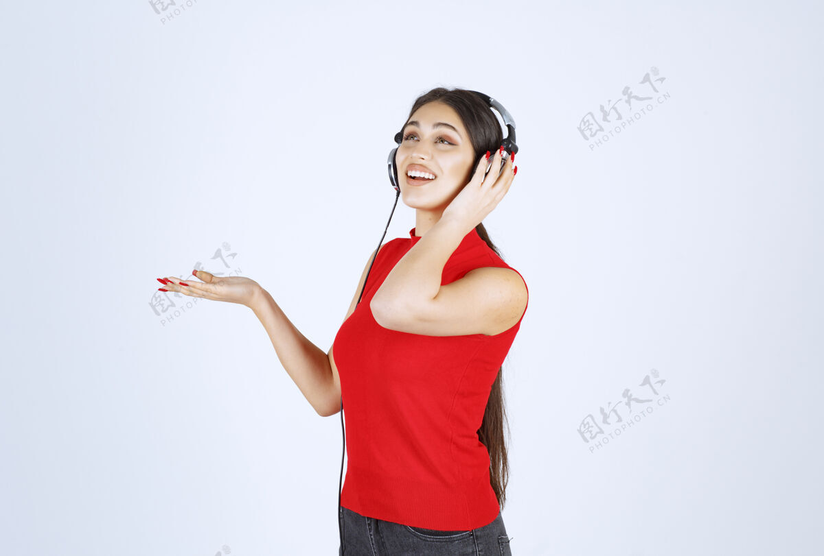 人类穿着红衬衫的Dj女孩 戴着耳机 手上拿着什么东西或是什么东西模特工作人员场景