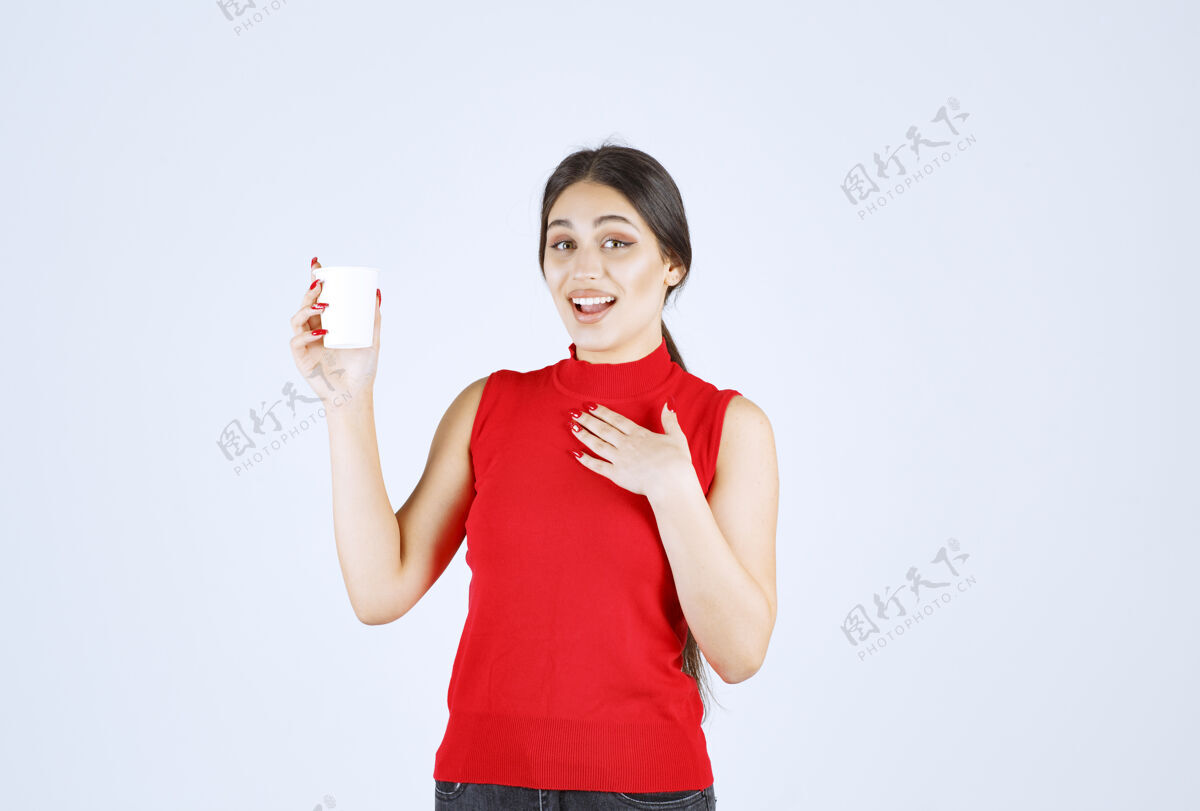 年轻人穿着红衬衫的女孩拿着一个白色的咖啡杯指着自己演讲年轻人女性