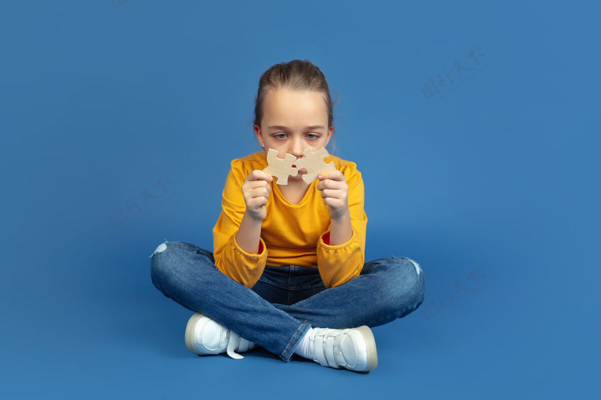 童年孤独地坐在蓝色工作室背景上的悲伤小女孩的肖像自闭症的感觉现代问题 社会问题的新视野自闭症的概念 童年 医疗保健 医学恐惧严重玩耍