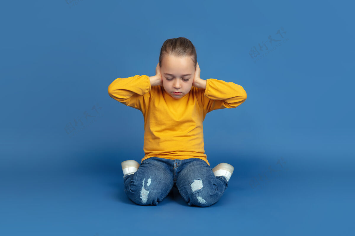 表情孤独地坐在蓝色工作室背景上的悲伤小女孩的肖像自闭症的感觉现代问题 社会问题的新视野自闭症的概念 童年 医疗保健 医学情绪孤独孤独