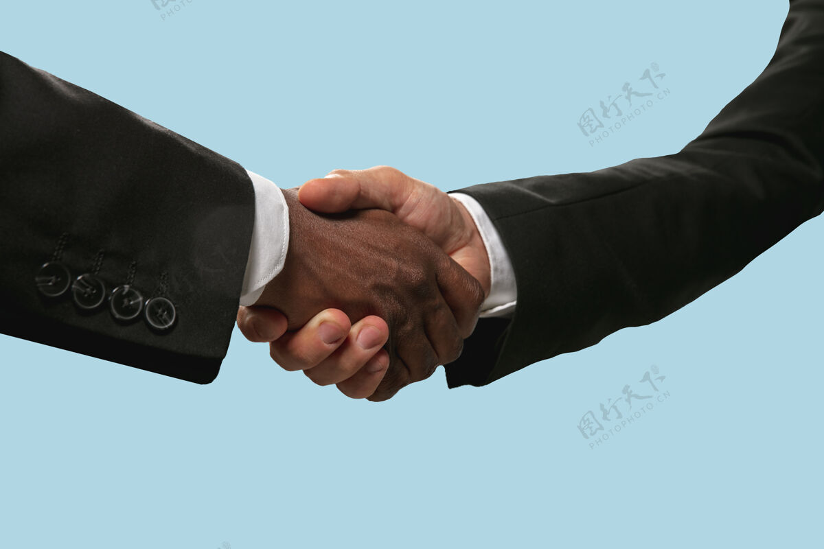 团结共同规划未来的标志团队合作和沟通两个男人的手在蓝色工作室背景上孤立地握手帮助 伙伴关系 友谊 关系 生意 团结的概念团队合作伙伴关系一起