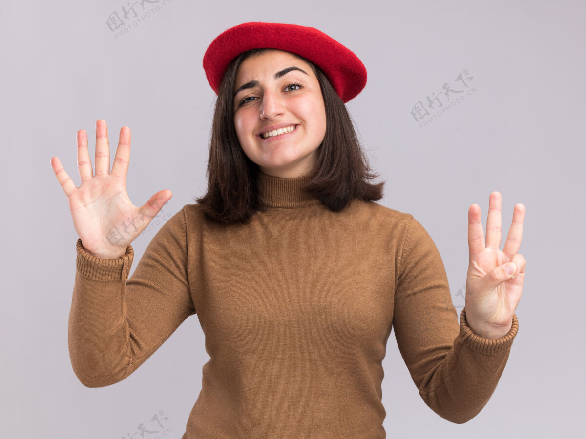 手指微笑着戴贝雷帽的年轻漂亮白人女孩用手指做着八个手势手势帽子漂亮