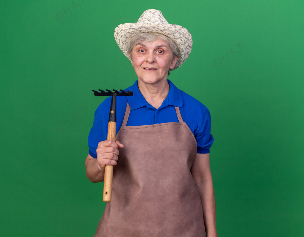 印象印象深刻的上了年纪的女园丁戴着园艺帽拿着耙子举行耙子园艺