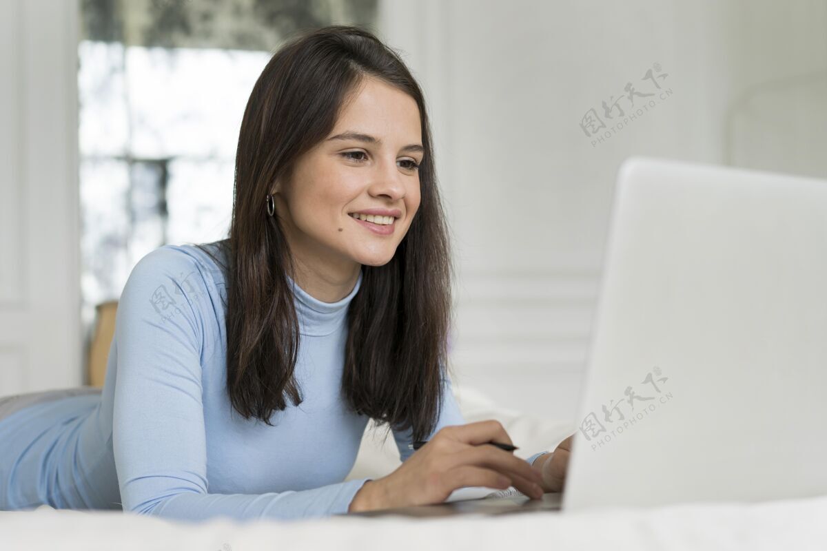 年轻人工作时躺在床上的女人女性笔记本电脑室内