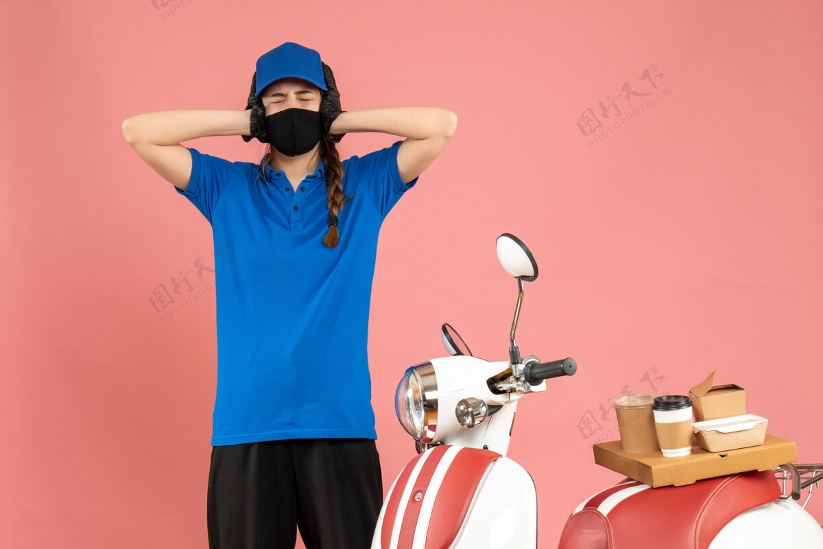 立场俯视图：疲惫的快递员戴着医用面罩站在摩托车旁 粉色背景上放着咖啡蛋糕背景医疗成人