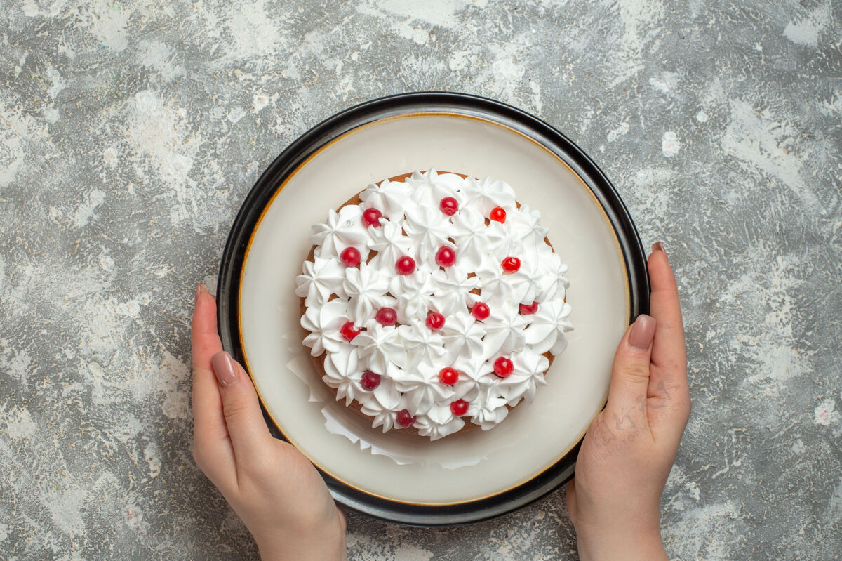蓝莓上图中 手拿着一个盘子 上面放着美味的奶油蛋糕 蛋糕上点缀着水果 背景是冰食物背景碗