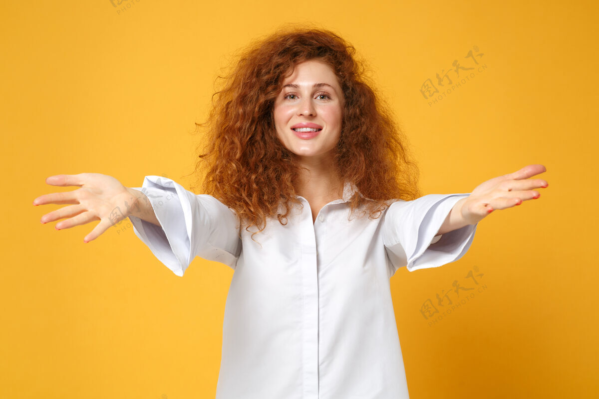 白种人微笑着的年轻红发女子穿着休闲白衬衫在黄橙色的墙上摆出孤立的姿势橙色女士手势