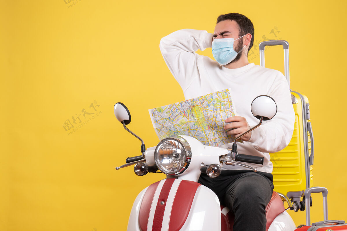 人旅行的概念 有麻烦的家伙在医疗面具坐在摩托车上黄色手提箱上成人旅行人