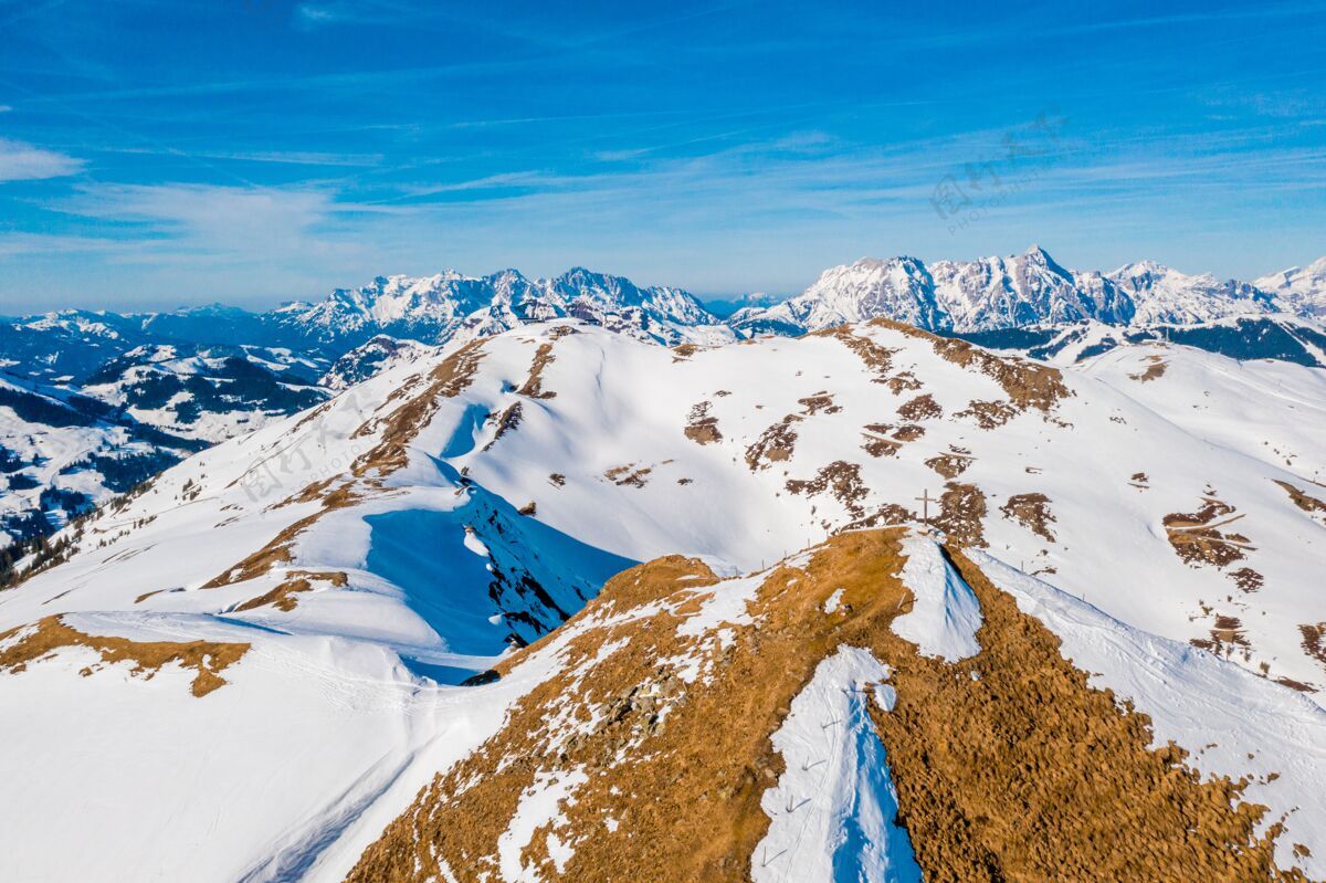 奥地利美丽的拍摄雪域覆盖的阿尔卑斯山与十字架上的一座山峰下的蓝天景观十字架度假村