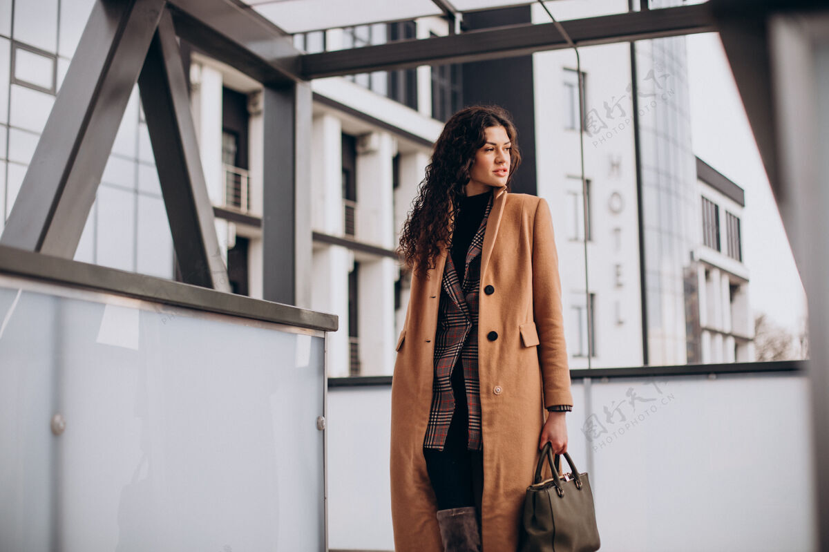 漂亮穿米色外套的女人在城里散步季节姿势外套