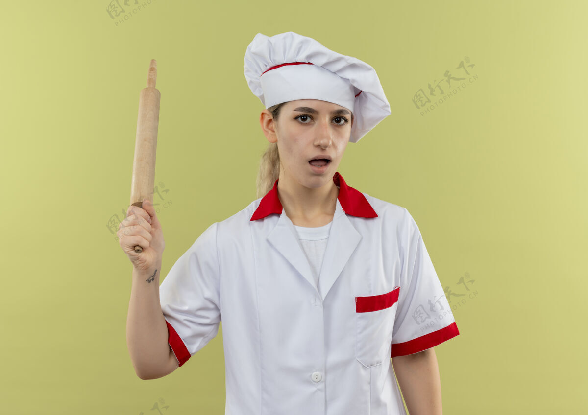 厨师年轻漂亮的厨师穿着厨师制服 手拿擀面杖孤立地站在绿色的墙上印象烹饪年轻