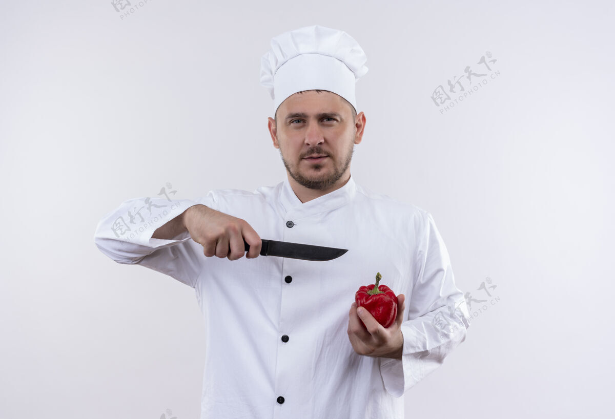 指着身着厨师制服的年轻帅哥自信地拿着胡椒粉 用刀指着隔离在白墙上的它年轻刀厨师