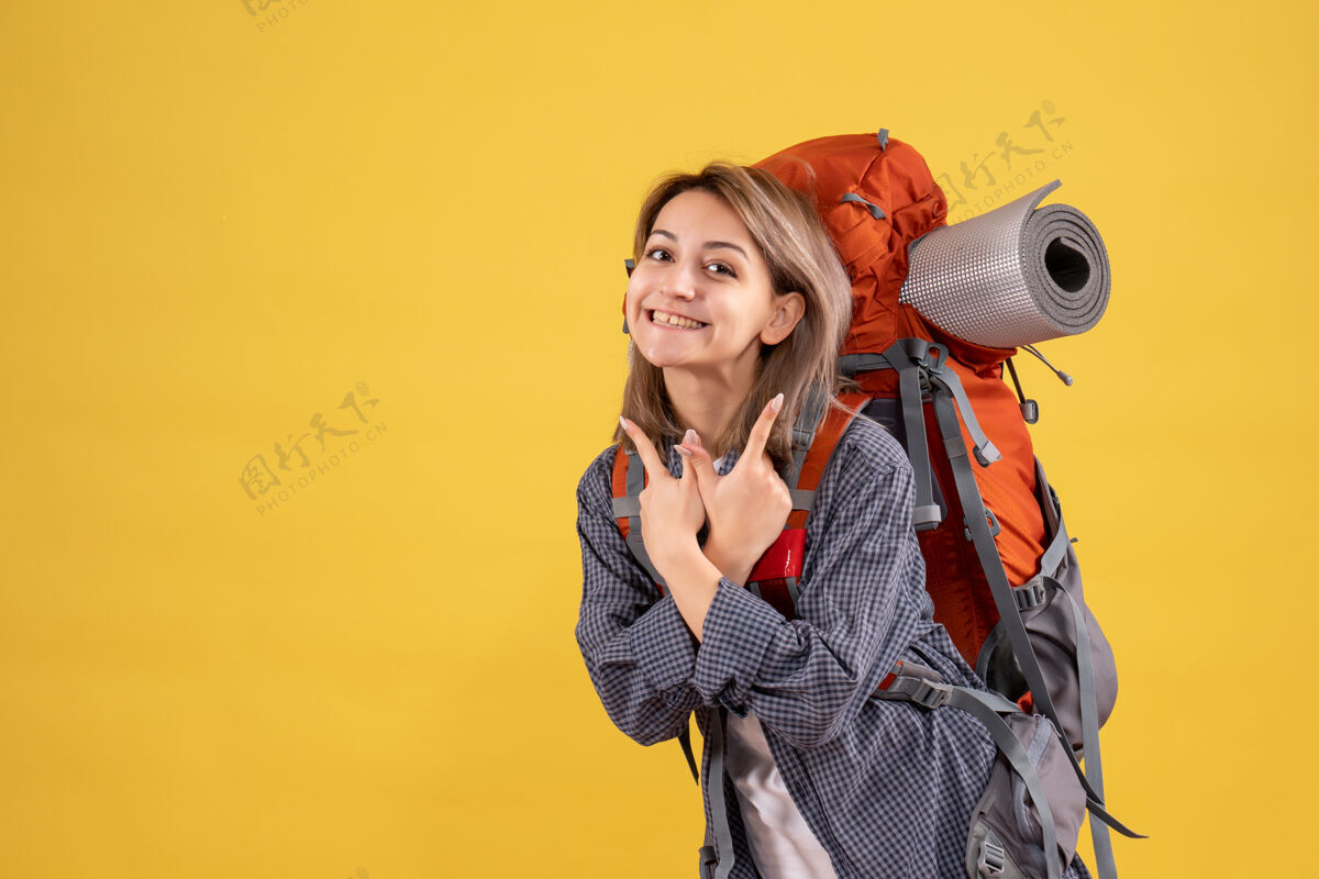 人带着灿烂笑容的旅行女人 背着红色的背包明亮三脚架肖像