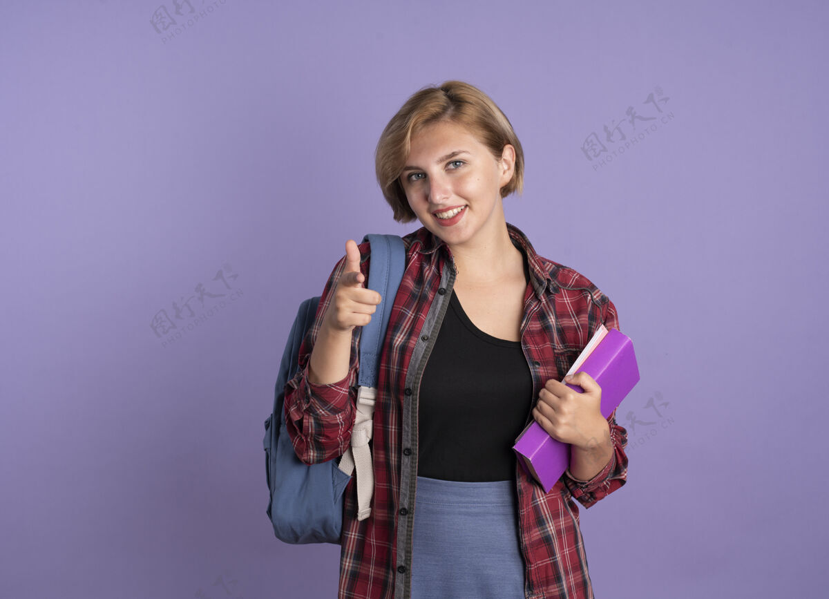 空间微笑着的年轻斯拉夫女学生背着书包拿着书和笔记本对着镜头女孩穿紫色