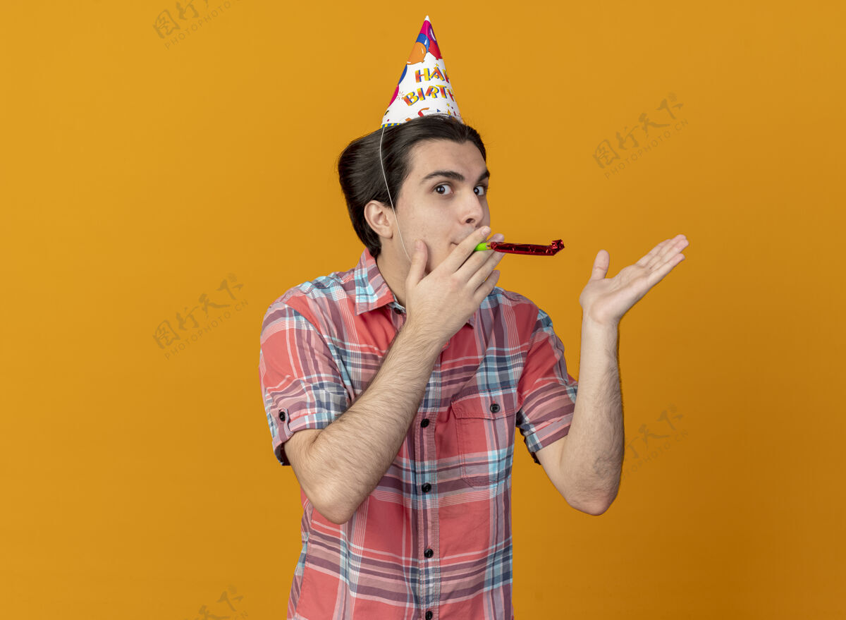 生日帅气的白种人戴着生日帽 手张开 吹着派对哨子吹哨子手