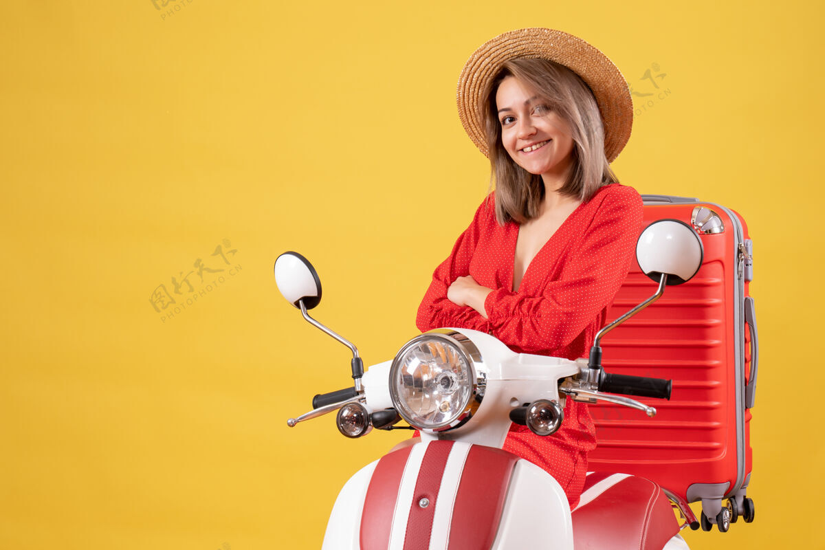 漂亮女孩骑着轻便摩托车 手交叉着红色手提箱的漂亮女孩红色摩托车汽车