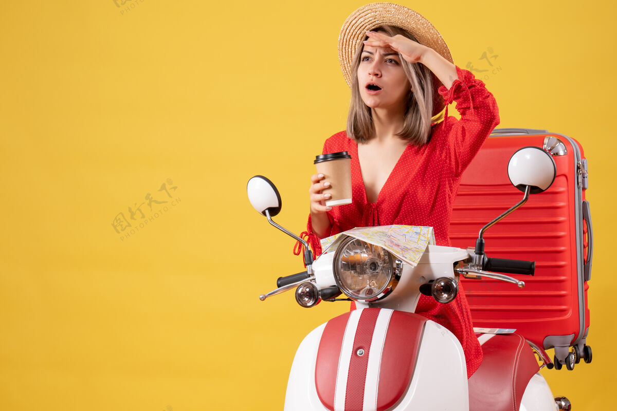 女人看着穿着红裙子的年轻女士拿着咖啡杯在轻便摩托车旁边成人欢乐杯子