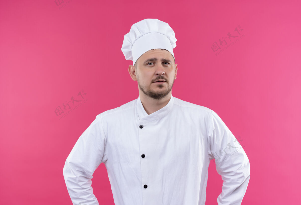 厨艺自信的年轻帅哥厨师身着厨师制服孤立在粉红色的墙上年轻厨师自信