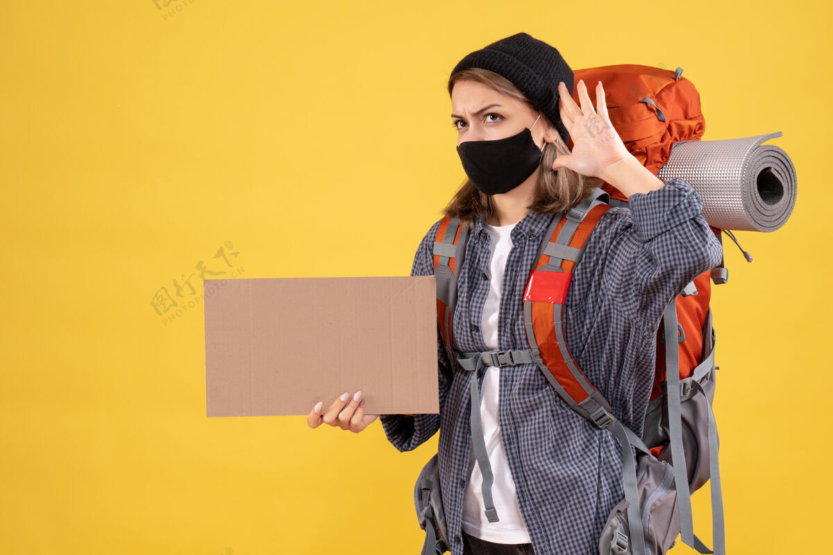 东西带着黑色面具和背包拿着纸板的旅行女孩在听什么面具成人女孩旅行者
