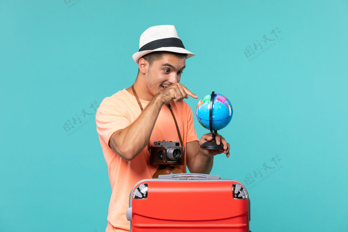 旅程度假的男人拿着地球仪用蓝色的相机拍照成人蓝色航行