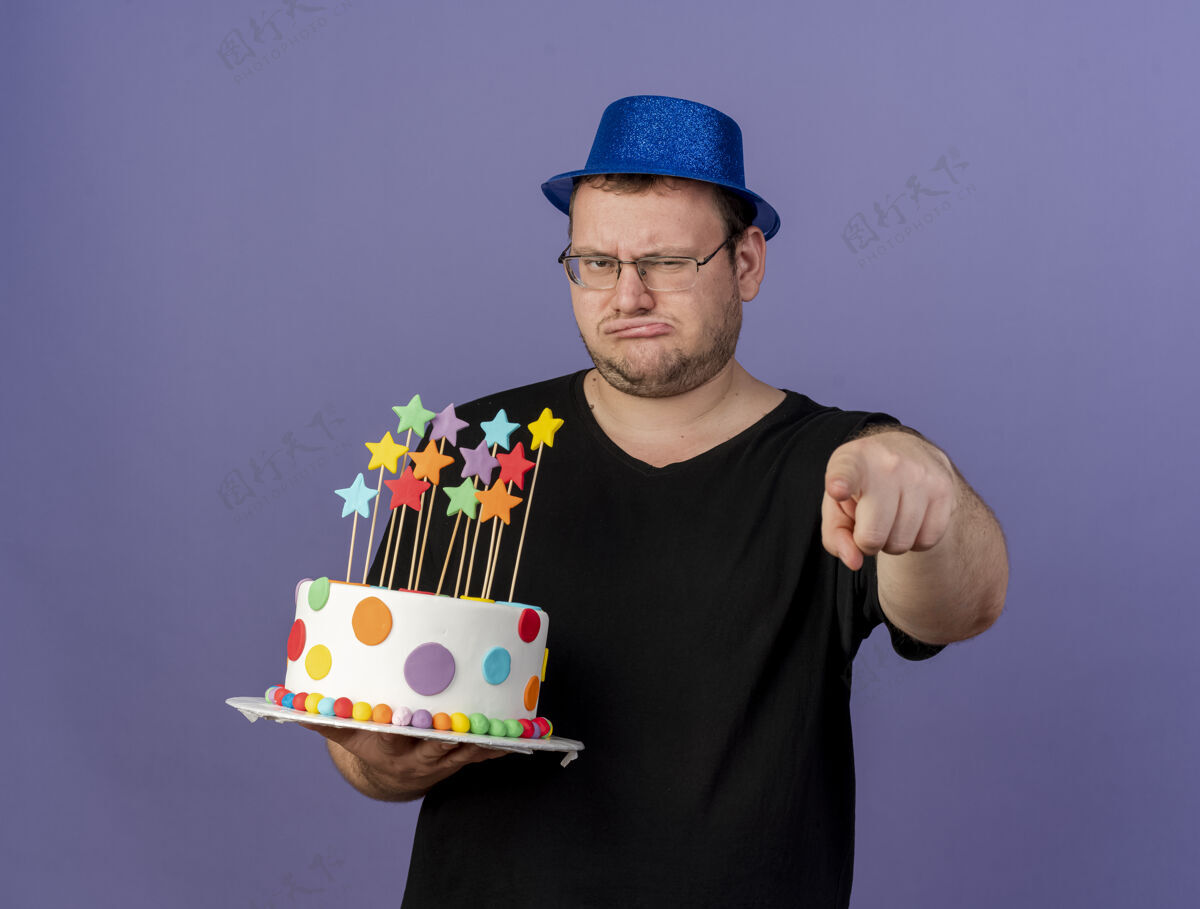 蛋糕一个戴着眼镜 戴着蓝色派对帽 拿着生日蛋糕 指着镜头的未被释放的成年斯拉夫人帽子生日不愉快