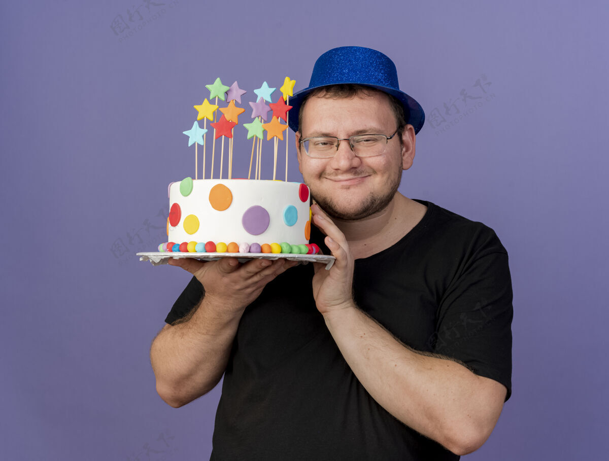 请高兴的成年斯拉夫人戴着眼镜戴着蓝色派对帽拿着生日蛋糕眼镜斯拉夫蛋糕