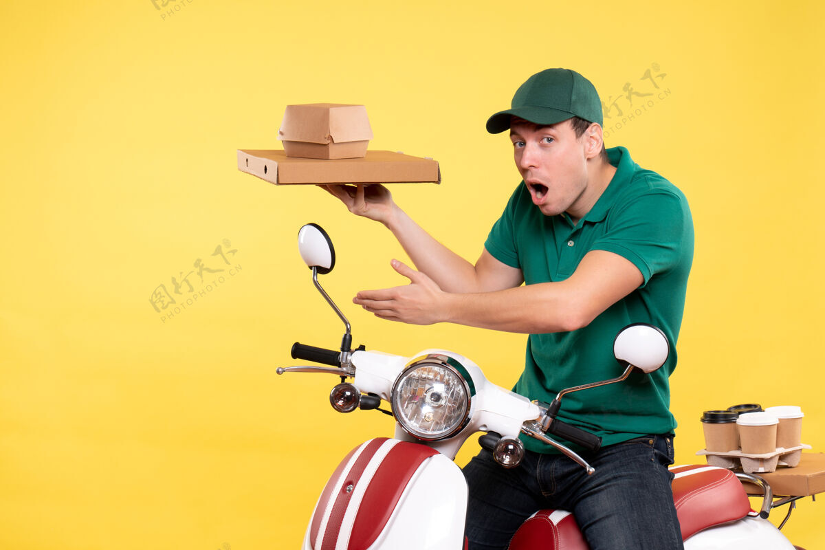 年轻男性信使正面图身着制服的年轻男性快递员手持黄色食品包装送货人摩托车