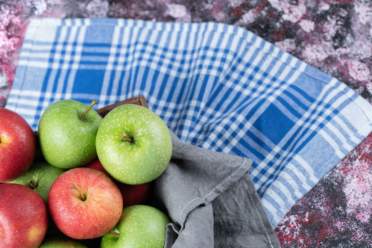 多汁红色和绿色的苹果被隔离在蓝色格子毛巾上异国情调美味水果