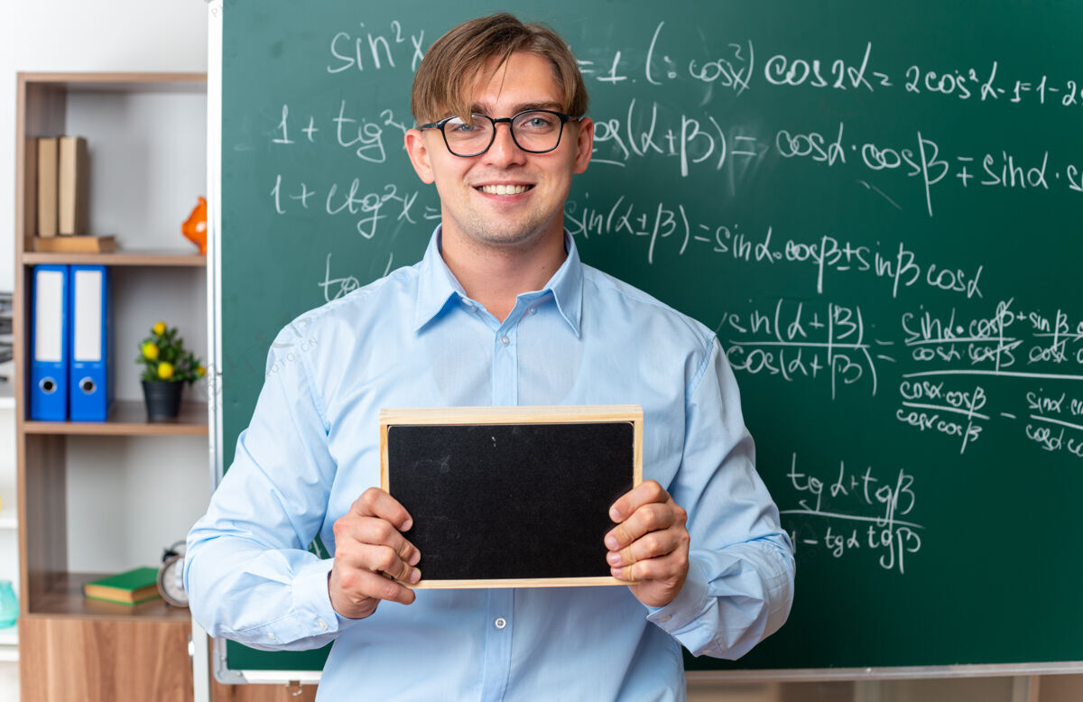 老师年轻的男老师戴着眼镜 拿着小黑板 面带微笑 自信地站在教室里的数学公式黑板旁眼镜公式数学