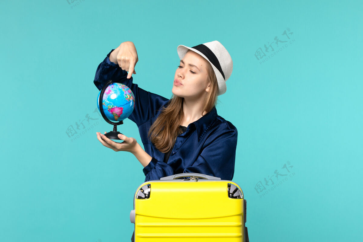 地球仪正面图年轻女子手持地球仪 准备在淡蓝色背景上度假女性旅程航海飞机度假年轻女子手持旅程