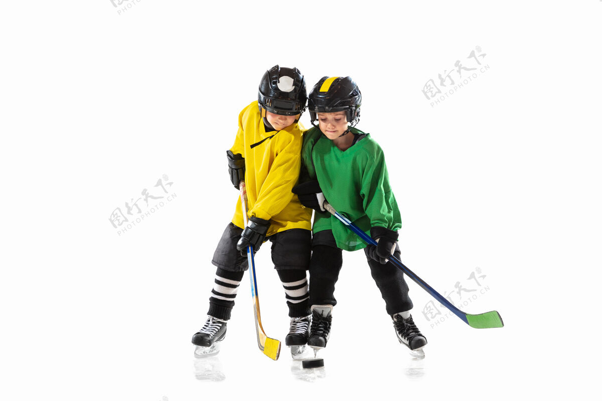 动作冰球场上拿着棍子的小冰球运动员和白色的工作室墙运动员专业曲棍球
