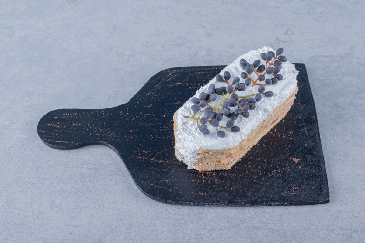 盘子新鲜的奶油蛋糕片和蓝莓放在黑色的木板上釉食物糖