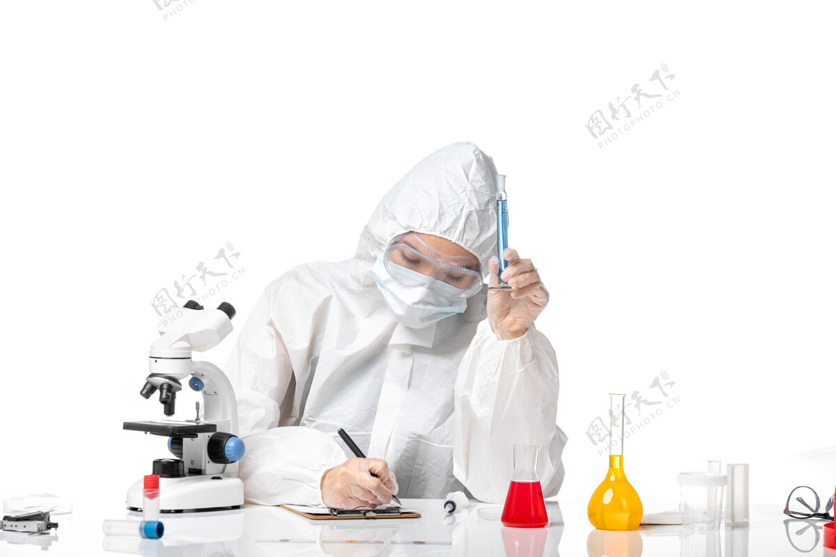 西装正面图年轻女医生穿着白色防护服 戴着口罩 因为柯维德拿着蓝色溶液在白色背景上写着大流行的柯维德病毒医学写作医生