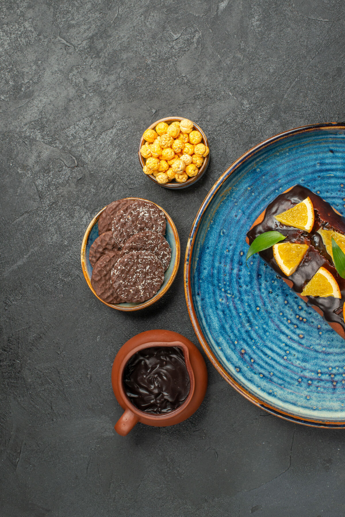 餐厅蓝色托盘上的美味蛋糕和深色背景上的饼干的垂直视图硬币碗杯子