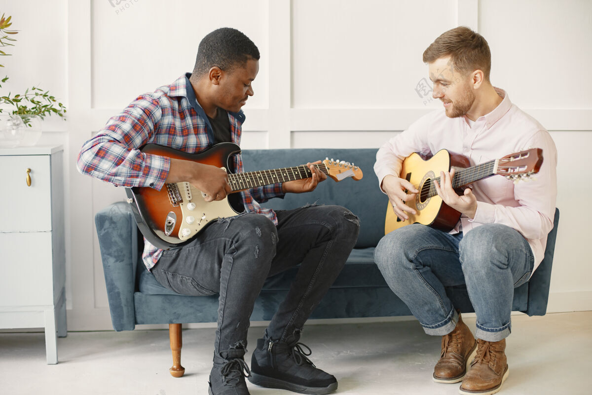 乐趣男人弹吉他 写音乐 非洲和高加索男人年轻家伙团结
